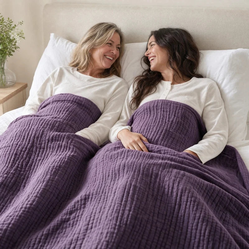 Two women in bed under the Muslin Blanket in Purple
